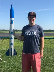 Sean Bartz holding a model rocket at a launch field